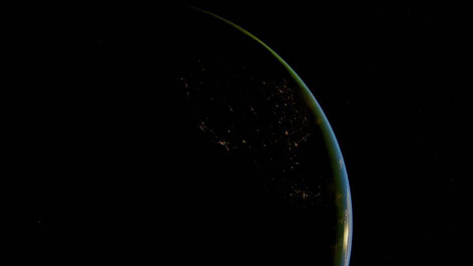 Beautiful aerial shot of Earth's horizon at night with city lights visible.