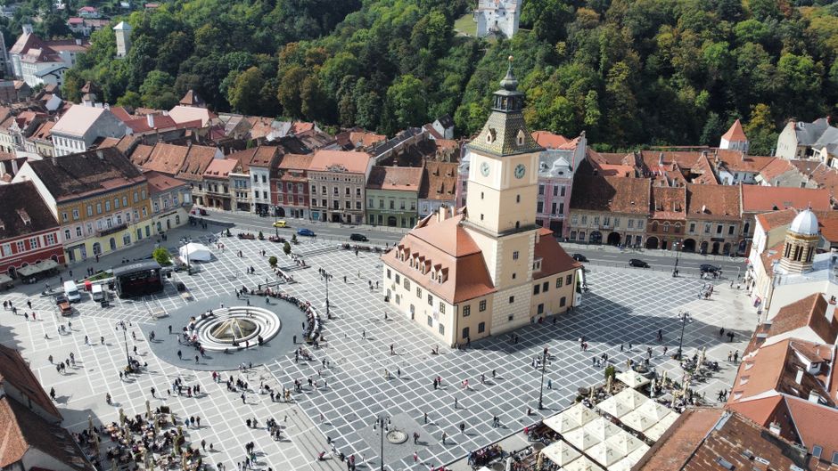 Aerial shot of the vibrant town square in Brașov, showcasing historic architecture and bustling activity.