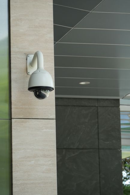 Close-up of a mounted security camera on a modern building's exterior.